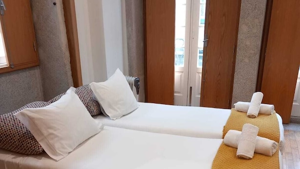A hotel room with two single beds, a wooden floor, and a view of the city through large windows. - Belomont6 Apartments (Porto)