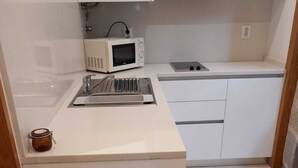 A compact kitchen with a microwave, sink, and cabinets. - Belomont6 Apartments (Porto)