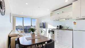 A modern apartment with a dining area, kitchen, and a sofa. - City Vista Apt with Views, Pool and Gym (Auckland CBD)