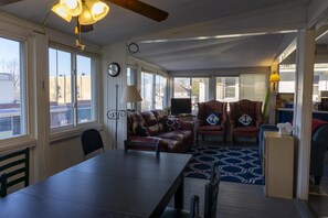 A spacious living area with a dining table, leather sofa, and two plaid chairs. A clock and a lamp are visible on the walls. - 223 Walnut Ave. in Lakeside (Lakeside)