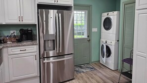 A compact kitchen with a stainless steel refrigerator, a coffee maker, and a washing machine. - 314 E. 3rd in Lakeside (Lakeside)