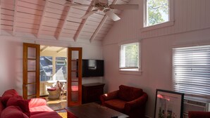 A cozy living room with a wooden ceiling, a television, a red sofa, a coffee table, and a framed picture. - 344 Maple in Lakeside (Lakeside)