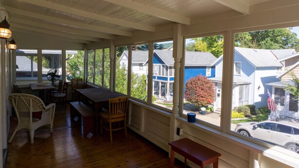 A covered porch with wooden flooring, a dining table, chairs, and a bench. - 344 Maple in Lakeside (Lakeside)