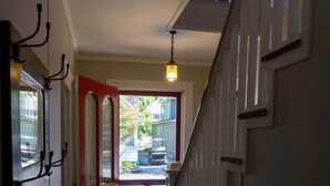 A hallway with a wooden floor, a red door, and a staircase with white railings. - 344 Maple in Lakeside (Lakeside)