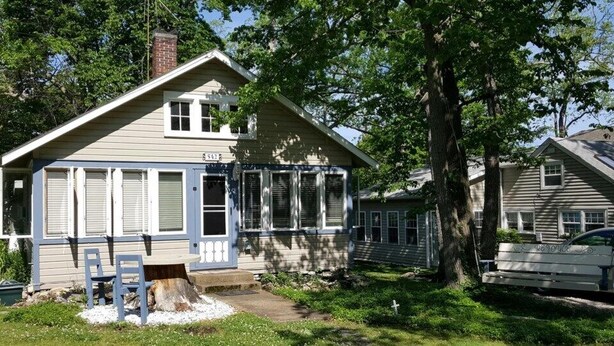 Une maison de plain-pied avec un porche à l’avant, une cheminée et une boîte aux lettres.