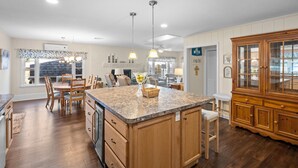 A spacious kitchen with a central island, wooden cabinets, and a dining area with chairs. - 660 Walnut Cottage in Lakeside (Lakeside)