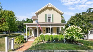 A two-story house with a porch, a small garden, and a flag. - 660 Walnut Cottage in Lakeside (Lakeside)
