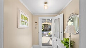 A hallway with a white door, a framed picture, a lamp, and a mirror on the wall. - 660 Walnut Cottage in Lakeside (Lakeside)