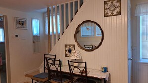 A staircase with a white railing, a mirror, and a table with chairs.
