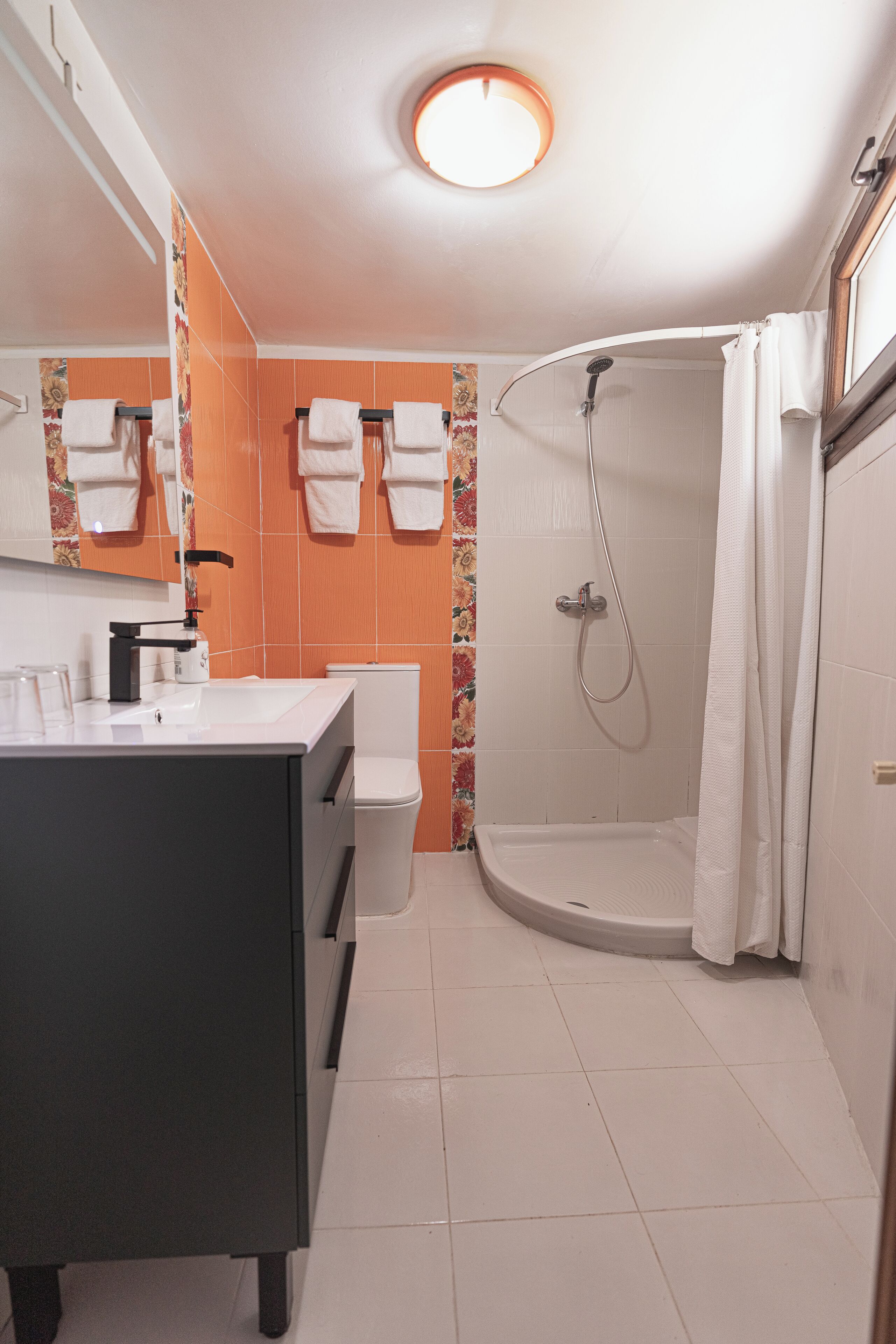 A bathroom with a white sink, toilet, and shower area.