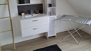 Ein modernes Schlafzimmer mit einer weißen Kommode, einem Spiegel, einem Regalsystem und einem Deckenventilator.