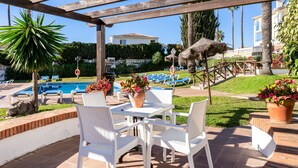 Un patio con piscina, sillas de descanso y una mesa con sillas.