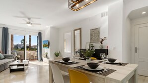 Una sala de estar moderna con comedor, ventilador de techo y vista al exterior.