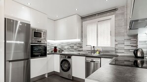 Una cocina moderna con electrodomésticos de acero inoxidable, lavadora y lavavajillas.