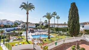 A pool area with lounge chairs, a pergola, and palm trees. - Colorful Flat in Riviera del Sol Ref 27 (Mijas)