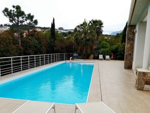 A swimming pool with a view of houses and trees in the background. - Magnificent villa with sea view and swimming pool (Sari Solenzara)