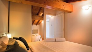 A bedroom with a bed, a nightstand, a lamp, and a wooden ceiling beam. - La Colombina (Verona)