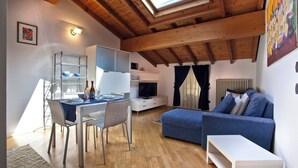 A cozy living space with a dining area, a television, and a blue sofa. - La Colombina (Verona)