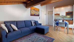 A living room with a blue sofa, a patterned rug, and a painting on the wall. - La Colombina (Verona)