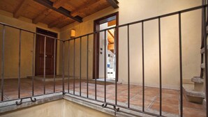 A corridor with a metal railing, a wooden door, and a view into a room with a tiled floor. - La Colombina (Verona)