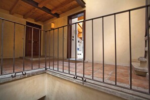 A corridor with a metal railing, a wooden door, and a view into a room with a tiled floor. - La Colombina (Verona)