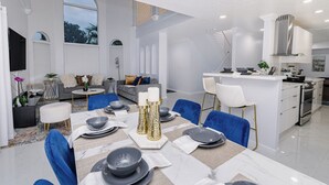 Cocina moderna con armarios blancos, campana extractora de acero inoxidable y una isla central con asientos.