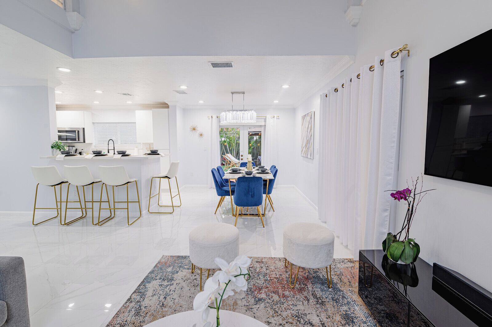 A modern kitchen with white cabinetry, a central island, and bar stools.