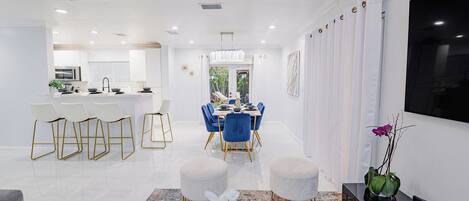 A modern kitchen with white cabinetry, a central island, and bar stools.