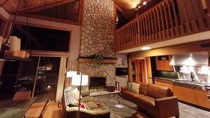 A cozy interior with a stone fireplace, a dining area, and a balcony with wooden railings.