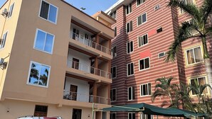Un edificio residenziale a più piani con balconi, auto parcheggiate e cielo sereno.