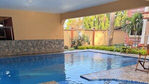 Una piscina con bordo piastrellato e fascia in pietra.