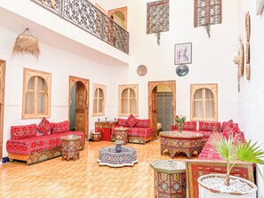 Un interior espacioso con sofás ornamentados, un techo alto y una decoración tradicional.