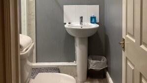 A bathroom with a toilet, sink, and mirror. - THE RATHMORE (Cambridge)