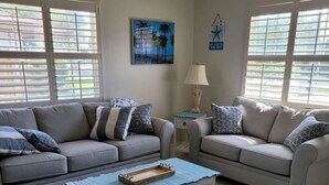 Ein Wohnzimmer mit zwei grauen Sofas, einem blauen Couchtisch und einem gemusterten Teppich.