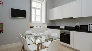 Una cocina moderna con armarios blancos, una mesa de comedor de vidrio y una encimera negra.