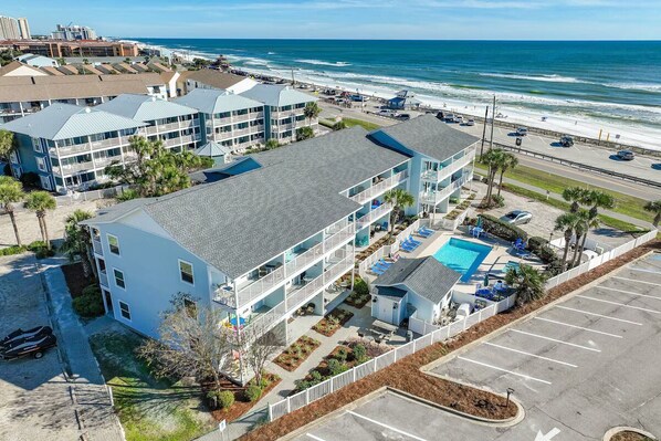 A beachfront hotel with multiple buildings, a swimming pool, and a parking area. - Steps to the beach! 1-bedroom condo in charming Miramar Beach (Miramar Beach)
