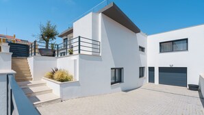 Un edificio moderno de dos pisos con techo plano, balcón y garaje.