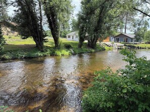 A river flowing through a wooded area with houses on the opposite bank.