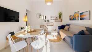 A modern living room with a dining area, a sofa, a TV, and artwork on the wall. - Elartis Apartment (Chania)
