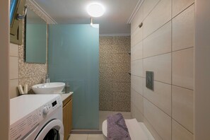 A compact bathroom with a washing machine, a sink, and a toilet. - Elartis Apartment (Chania)