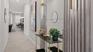 A modern hallway with a glass console table, a potted plant, and a framed artwork on the wall. - Amazing 6bed Home in Solara Fun for All (Kissimmee)