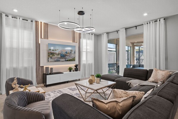 A modern living room with a large flat-screen TV, a sofa, a coffee table, and a console table with decorative items.