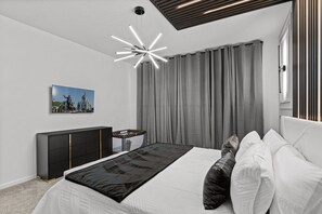 A modern bedroom with a large bed, a black and white color scheme, a unique ceiling light, and a picture on the wall.