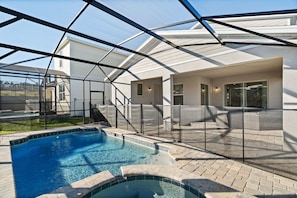 A swimming pool with a glass enclosure, a covered patio area, and a staircase leading to a second level. - Amazing 6bed Home in Solara Fun for All (Kissimmee)