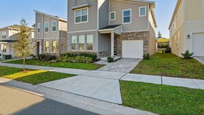 A modern two-story townhouse with a garage, a well-maintained lawn, and a clear sky. - Amazing 6bed Home in Solara Fun for All (Kissimmee)