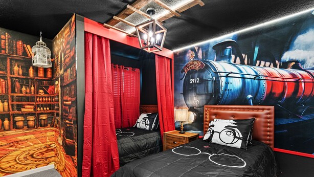 A bedroom with a red canopy bed, a bookshelf, and a large wall mural of a train. - Amazing 6bed Home in Solara Fun for All (Kissimmee)