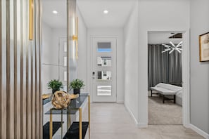 A modern hallway with a glass table, potted plants, and a bench. - Amazing 6bed Home in Solara Fun for All (Kissimmee)