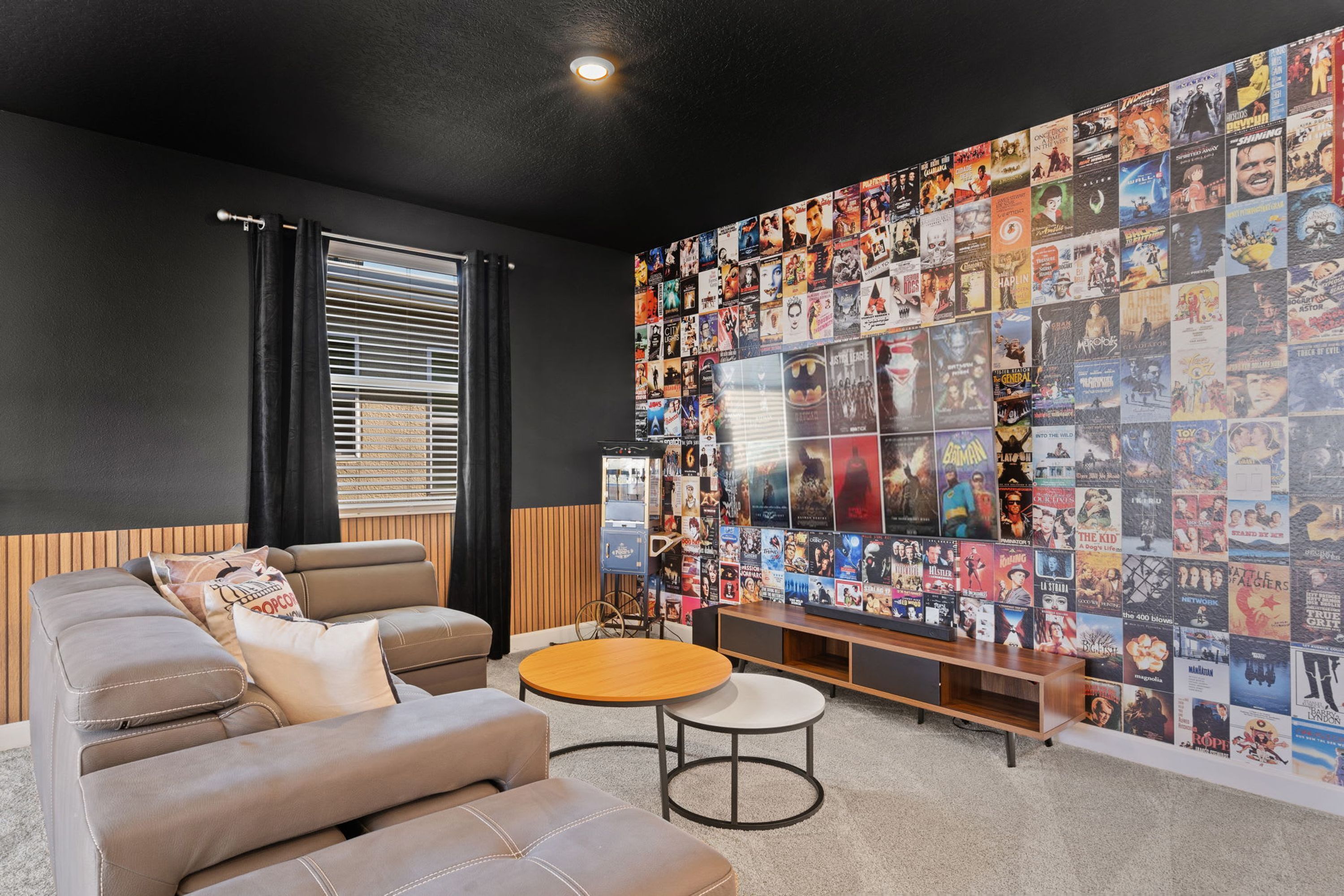 A modern living room with a sofa, a round coffee table, and a wall covered with movie posters.