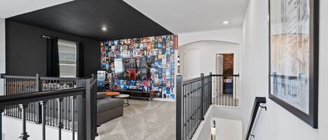 Un interior moderno con una escalera, una pared de carteles de películas y una zona de estar acogedora.