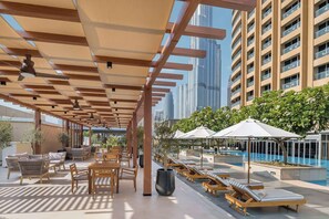 A rooftop pool area with lounge chairs and tables, surrounded by tall buildings. - Lovely Studio Burj Khalifa View (Dubai)